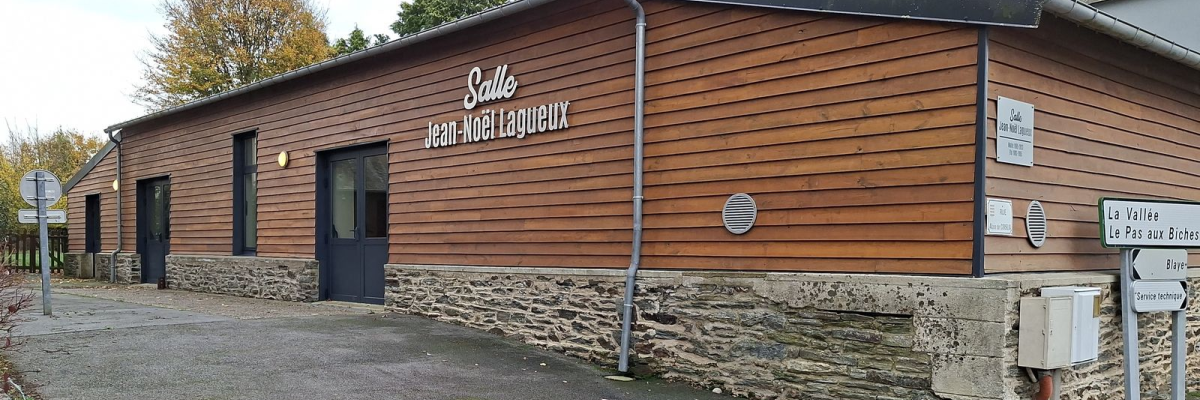 "Bâtiment extérieur avec façade en bois, porte, fenêtres, et panneaux indicateurs."