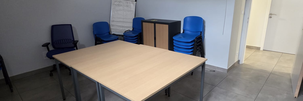 Salle avec table, chaises, tableau blanc et porte.