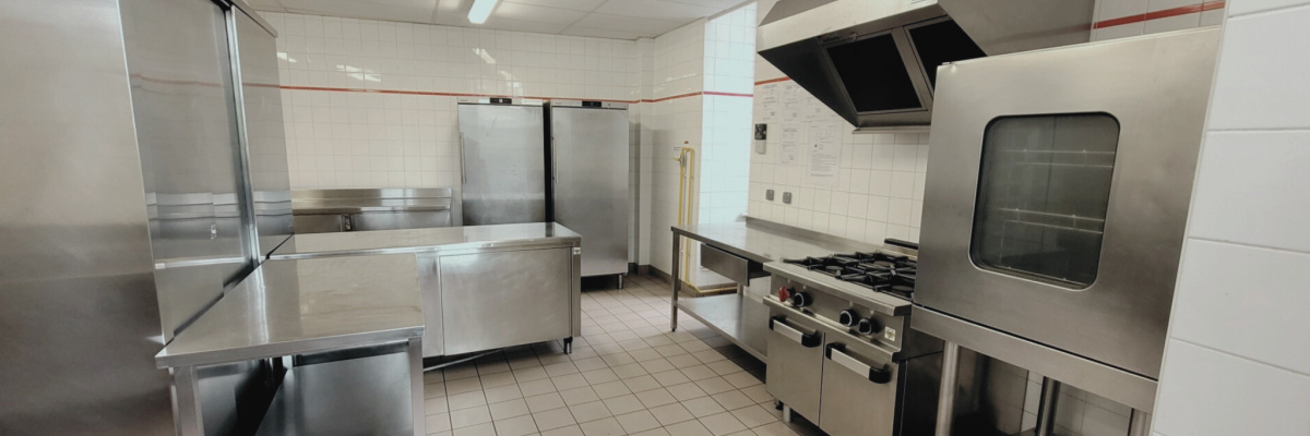 Cuisine équipée avec plans de travail, fours, plaques de cuisson, armoires et hottes.