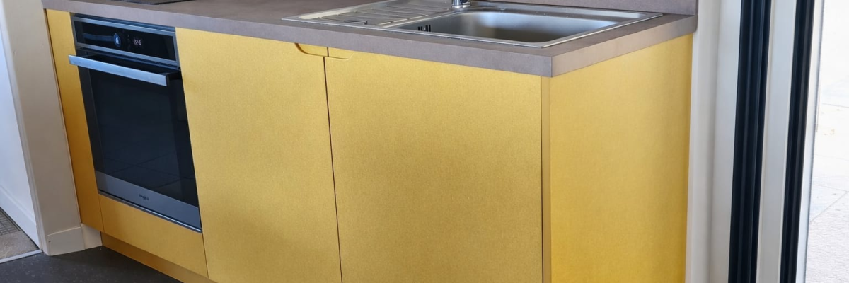 Cuisine avec plans de travail, évier, robinet, plaque de cuisson et four intégrés.