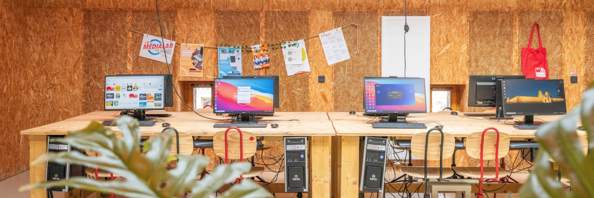 Salle avec cinq postes de travail, chaque poste équipé d'un écran, d'un clavier, d'une souris et d'une tour d'ordinateur.