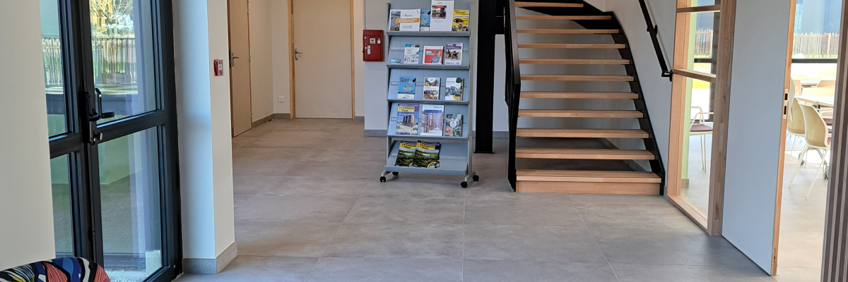 Espace ouvert avec canapé, escalier, étagères à livres et portes vitrées.