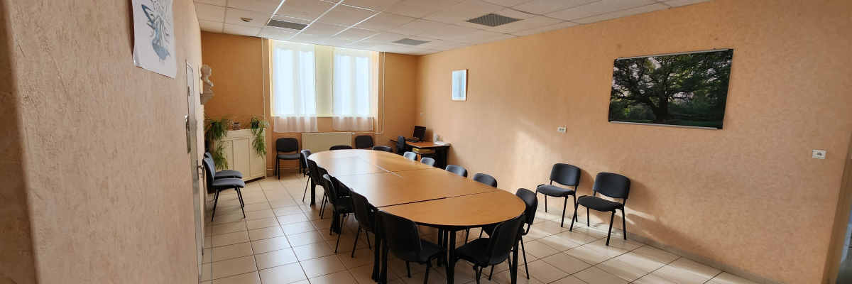 Salle de réunion avec table ovale, chaises, tableaux et plantes.