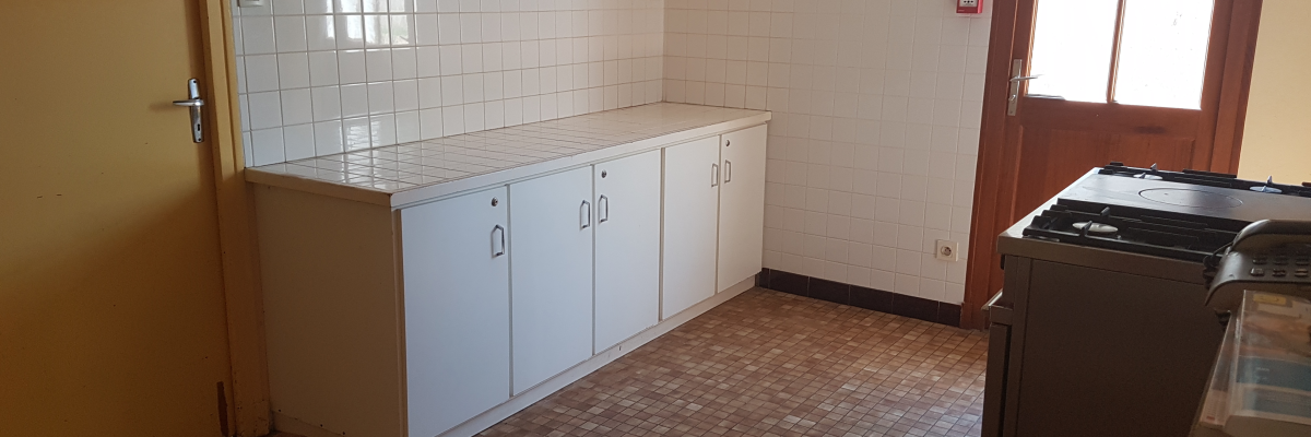 Cuisine avec placards, plan de travail, porte et fenêtre.