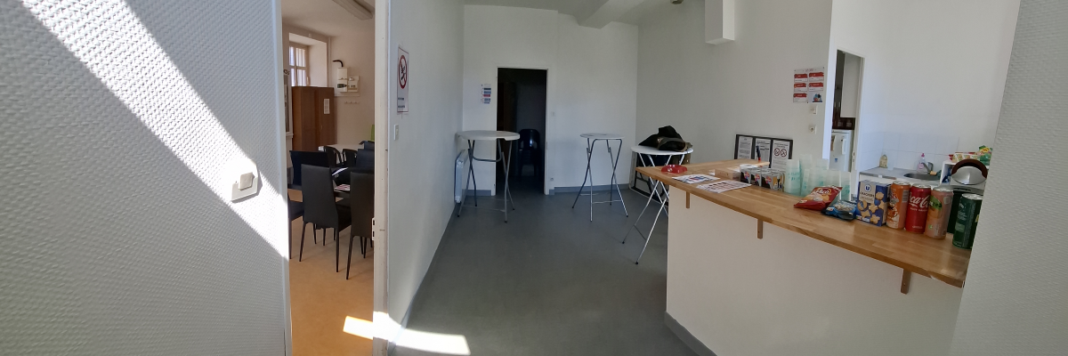 Pièce avec comptoir, chaises, table de réunion, canapé et diverses fournitures.