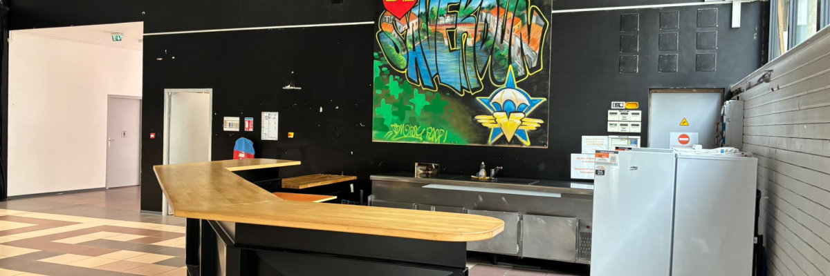 Espace avec table, écran, distributeur de boissons et porte.