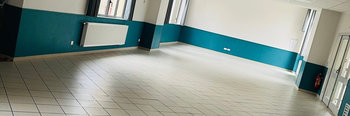 Salle vide avec carrelage, murs teintés, portes et plafond à dalles.