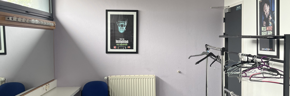 Pièces avec étagères, porte-manteaux, radiateur, chaises et tableau.