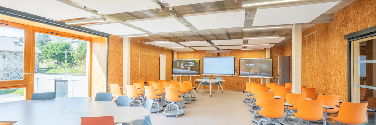 Salle de classe avec tables, chaises, tableau blanc et projecteur.