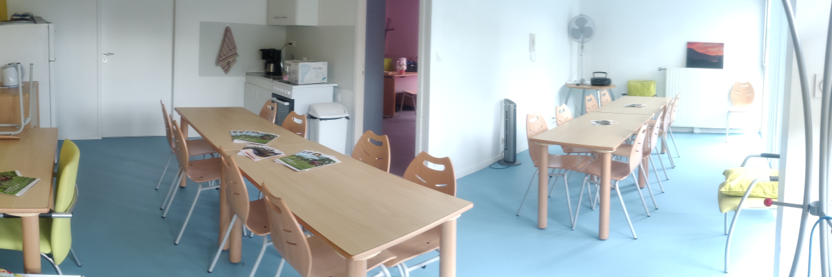 Salle avec tables, chaises, ventilateurs, étagères, micro-ondes et porte-manteau.