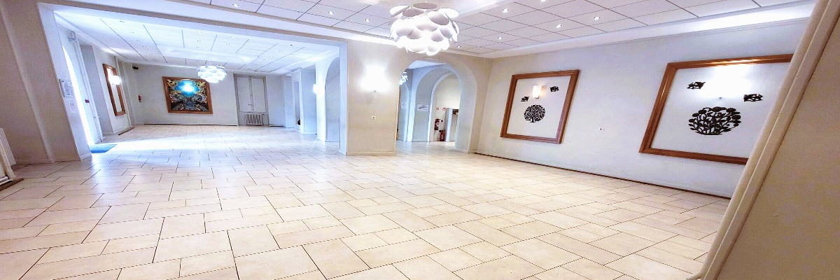 Grand espace intérieur avec carrelage, luminaires suspendus, cadres et portes.