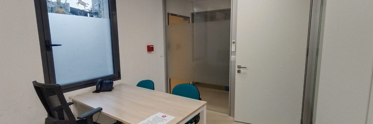 Salle avec table, chaises, téléphone, porte vitrée et porte blanche.