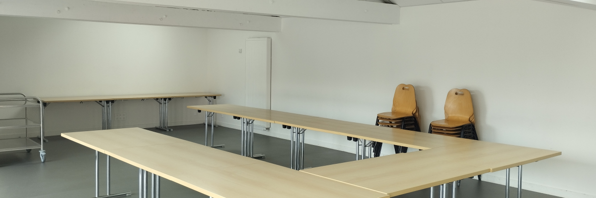 Salle avec tables, chaises et chariot.