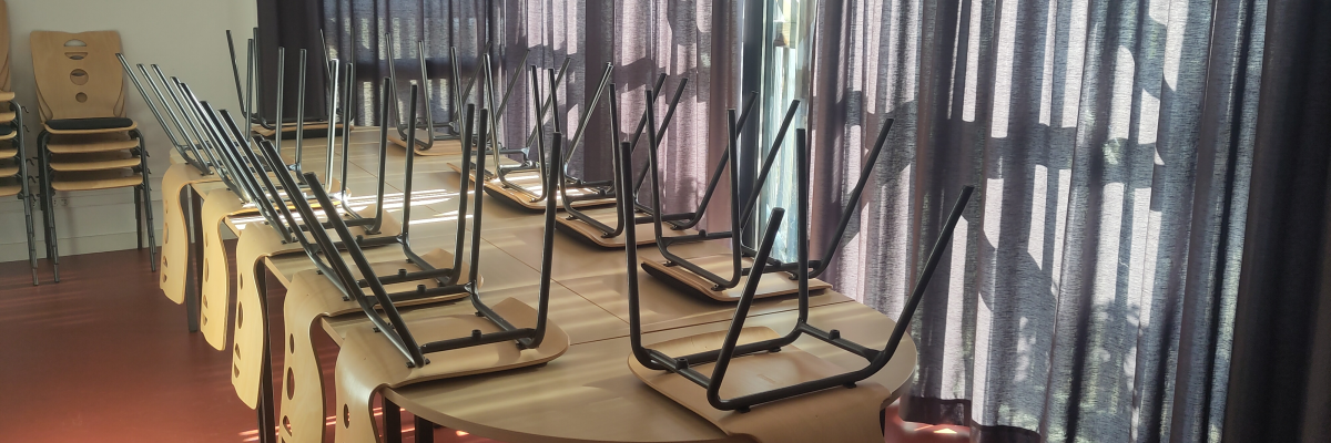 Salle avec tables, chaises, rideaux et fenêtres.