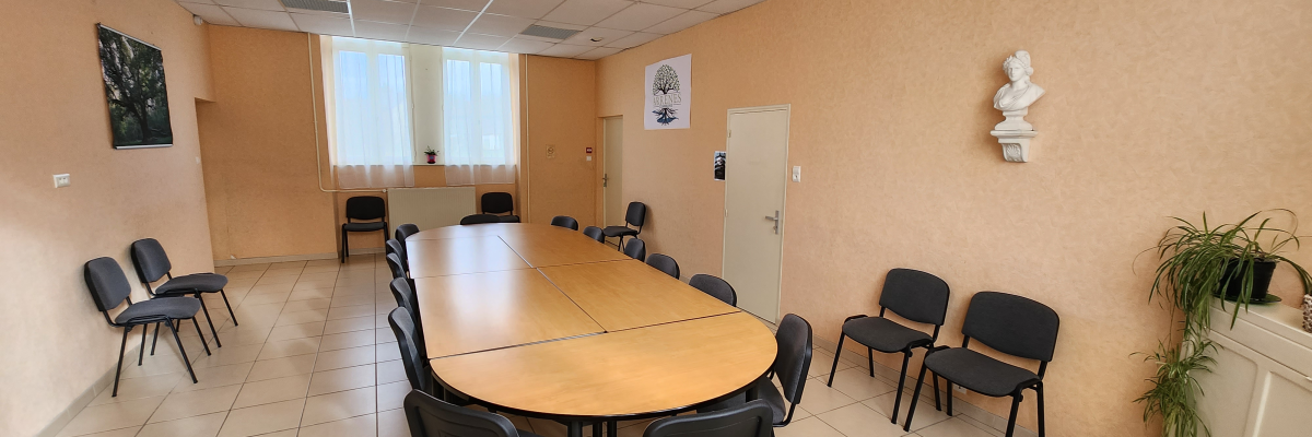 Salle de réunion avec table ovale, chaises, porte, fenêtre et plante.