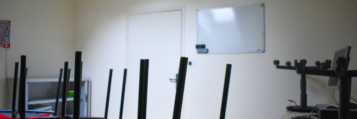 Salle avec table, chaises à ballon, tableau blanc, écran, ordinateur et matériel audio.