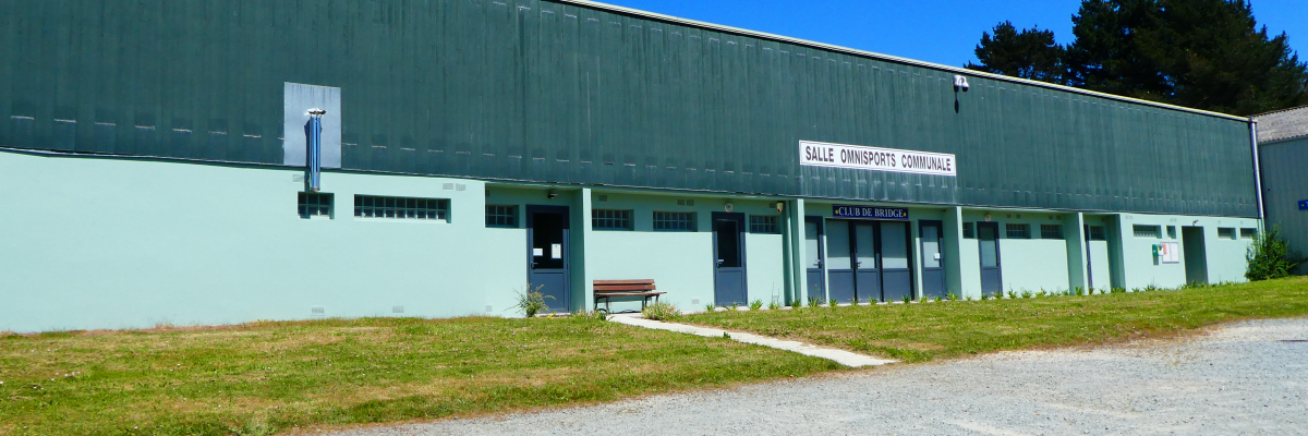 Bâtiment industriel avec entrée, enseigne et banc.