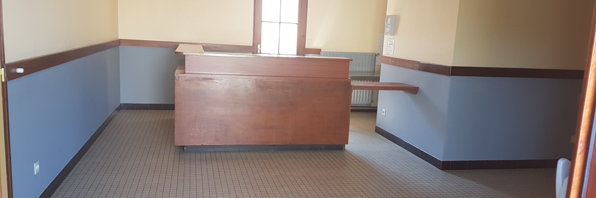 Salle avec bureau, sol carrelé, porte et radiateur.