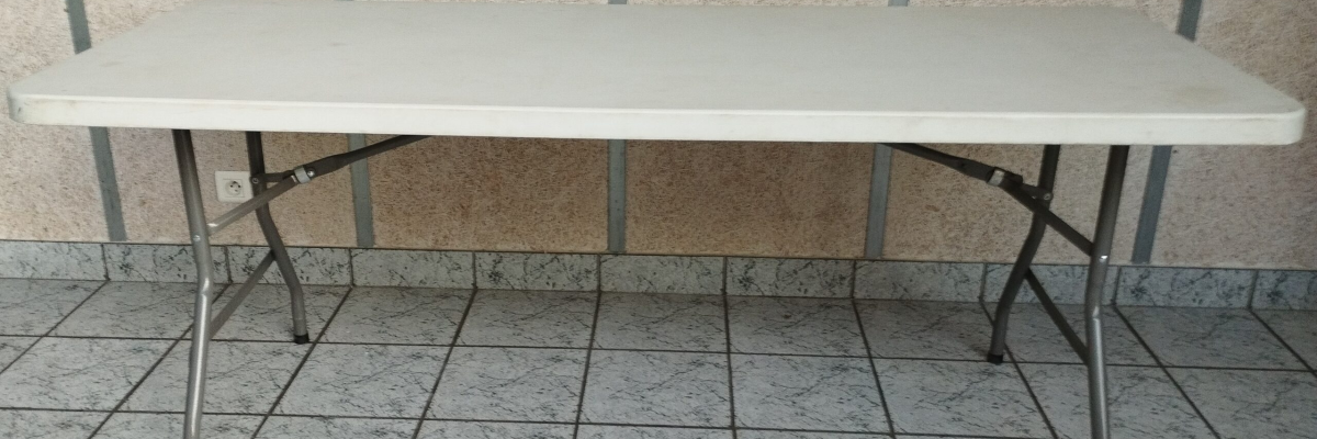 Table blanche avec tréteaux et pieds métalliques sur carrelage.