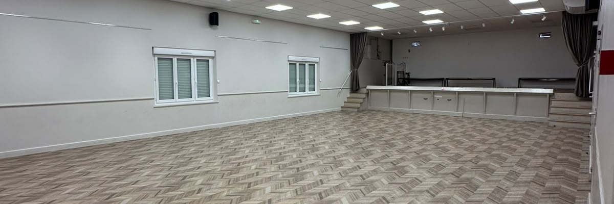 Salle vide avec moquette, lumières, fenêtres et climatiseur.