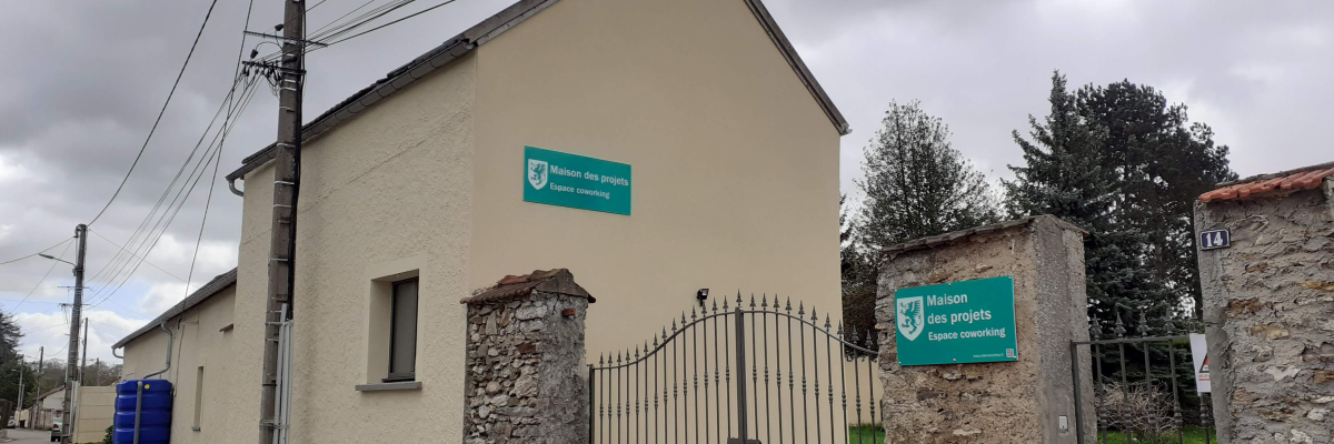 Bâtiment avec enseigne "Centre Social et Culturel Armand Mergnac", portail en fer, murs en pierre et clôture. Rue avec lampadaire et fils électriques.