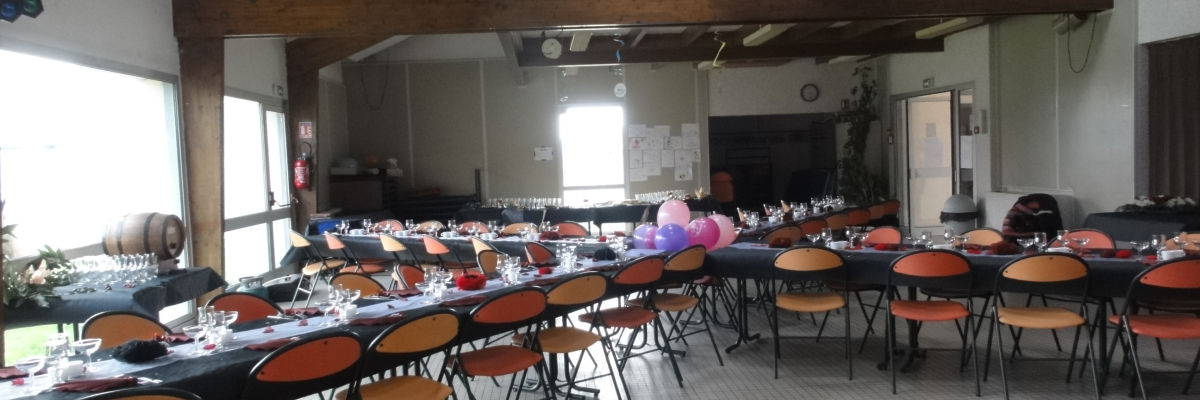 Salle avec tables, chaises, vaisselle, ballons, matériel de projection et équipement audio.