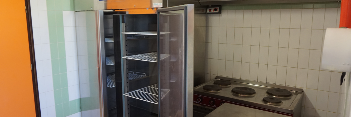 Cuisine avec réfrigérateur, plaque de cuisson et hotte.