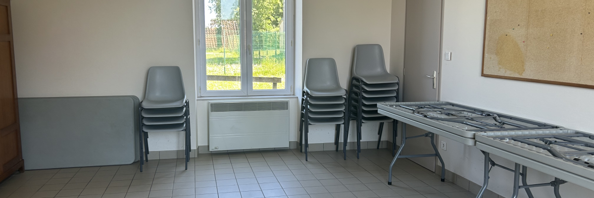 Salle avec tables, chaises, tableau et fenêtre.