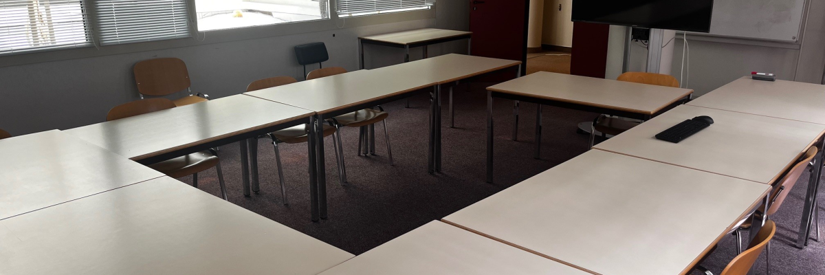 Salle avec tables, chaises, écran, vidéo projecteur et tableau.