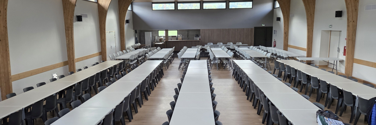 "Salle avec rangées de tables, chaises, et tableau à l'avant."