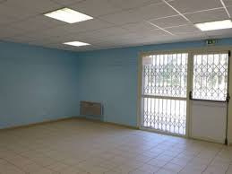 Pièce vide avec éclairage au plafond, grille de ventilation, climatiseur mural et portes vitrées avec barreaux.