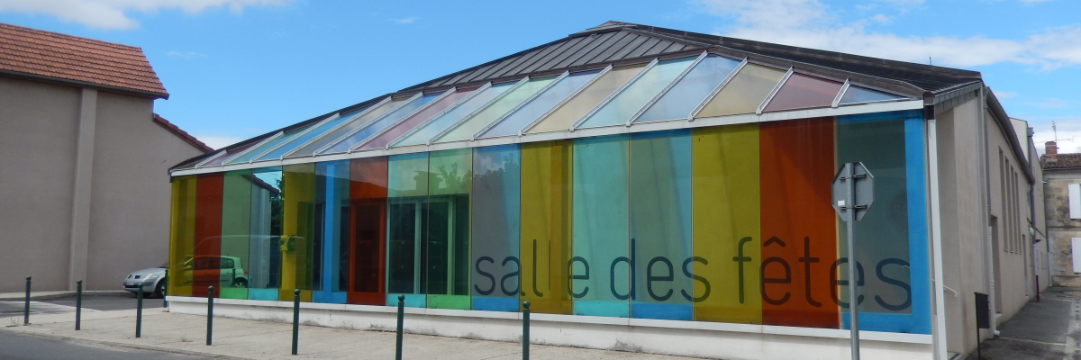 Bâtiment avec façade vitrée colorée, porte et escalier extérieur.