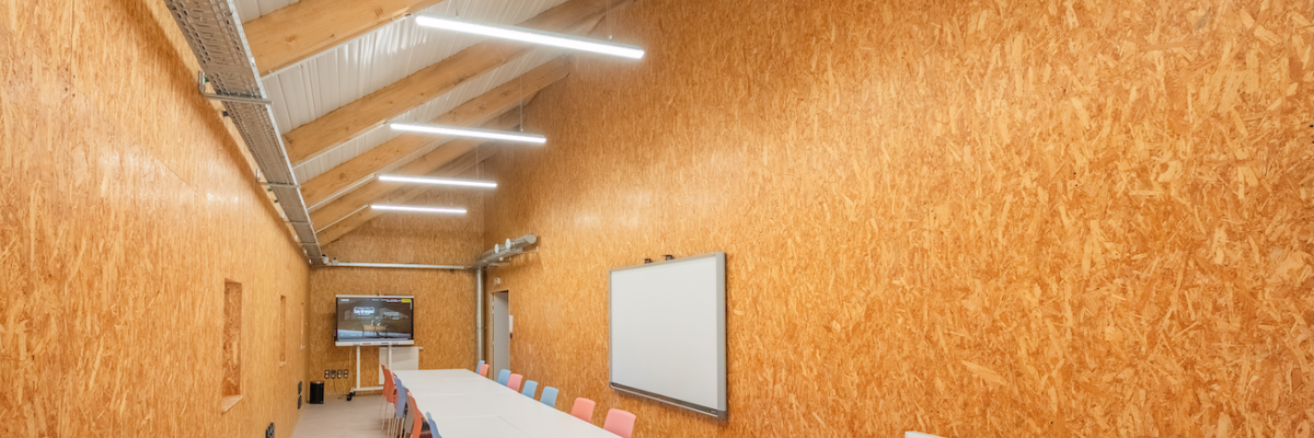 Salle avec table, chaises, tableau blanc et radiateur.