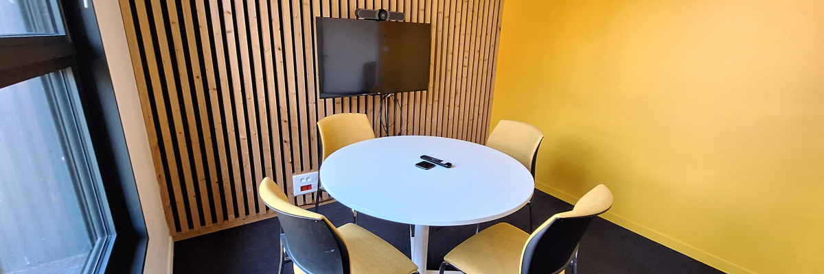 Salle avec table ronde, quatre chaises, télévision et climatiseur.