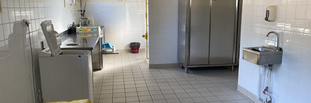 Cuisine avec évier, lave-linge, armoire, table et chaises.