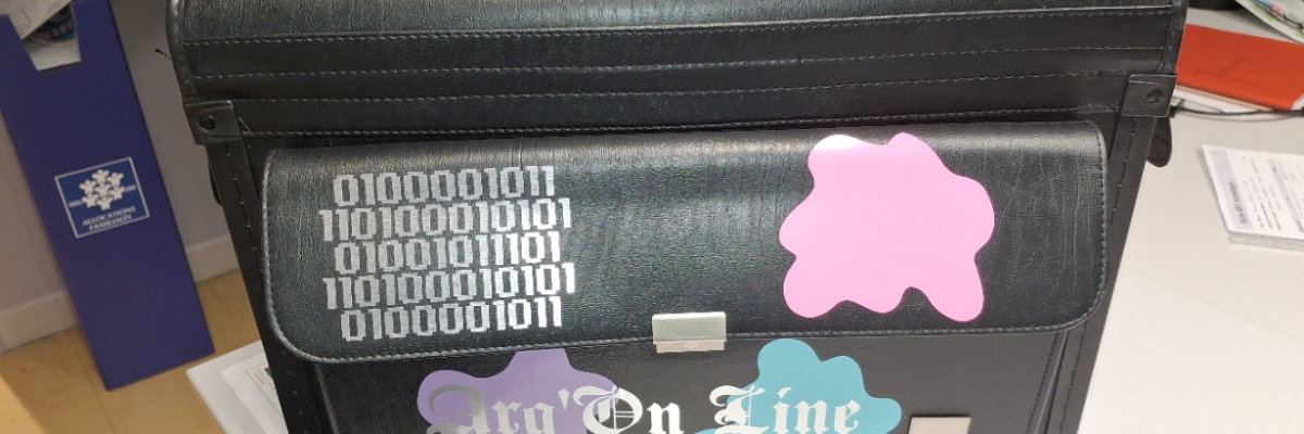 Valise noire avec autocollants et inscriptions, posée sur une table.