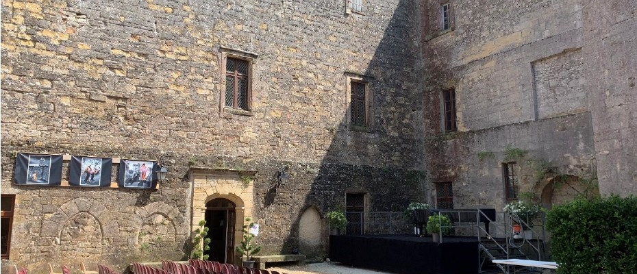 Cour extérieure avec chaises, écrans, scène et table.