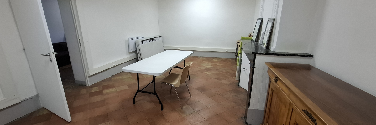 Pièce avec table, chaises, armoire, étagères et porte ouverte.