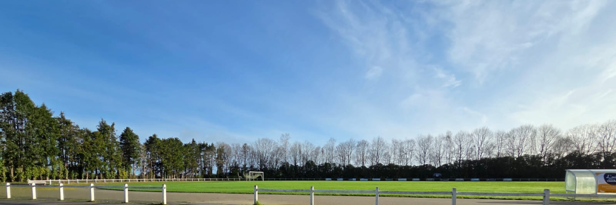Terrain de sport avec parking, clôture et but de football.