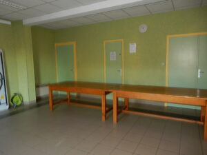 Salle avec table, chaises, portes, horloge et climatiseur.