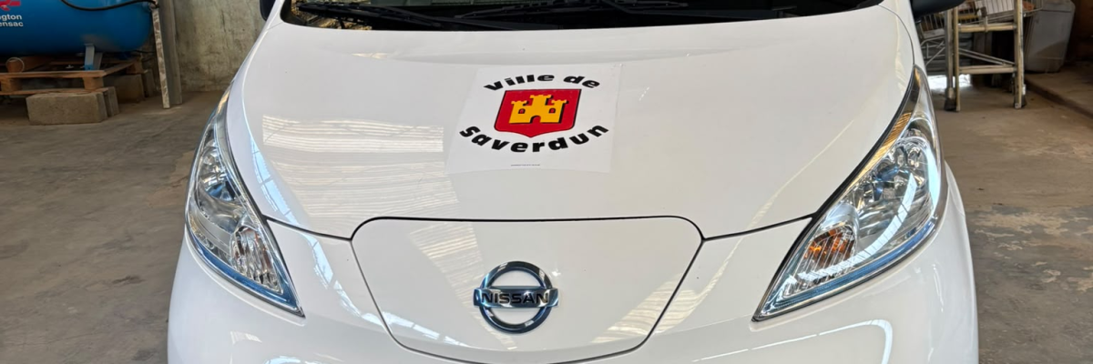 Voiture blanche devant un entrepôt.
