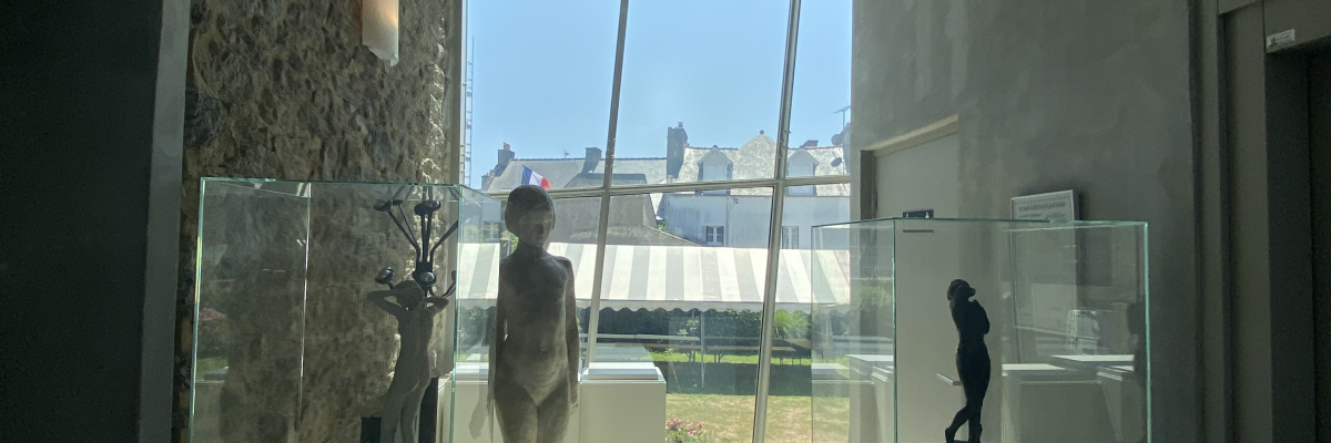 Galerie d'art avec sculptures, vitrines et portes.