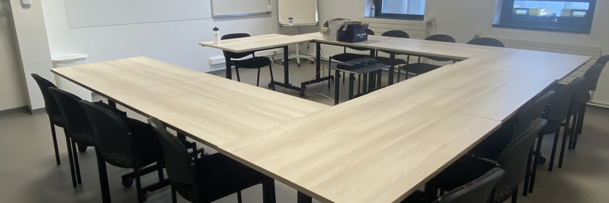 Salle de réunion avec table, chaises, vidéo projecteur et tableau blanc.