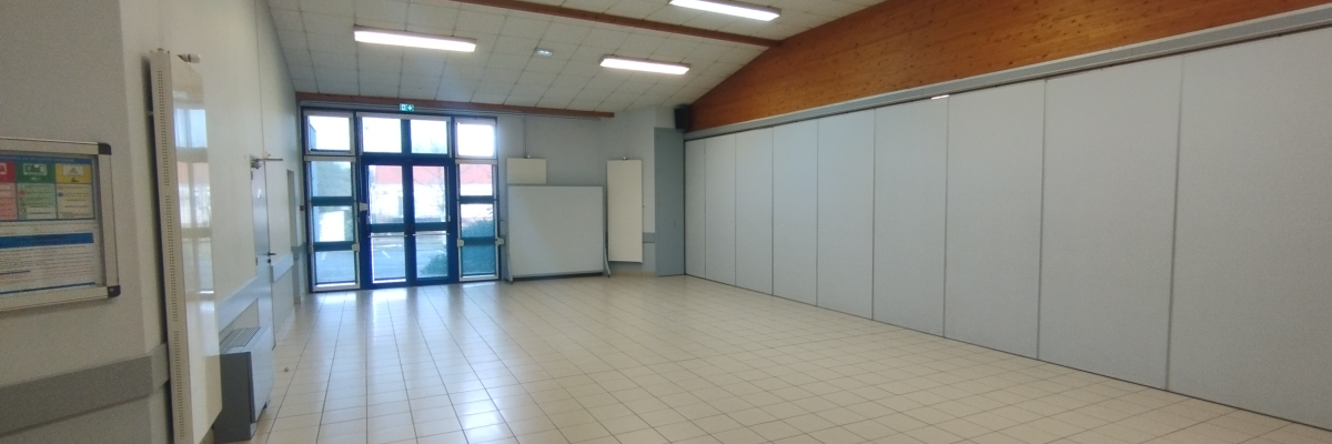 "Salle vide avec porte vitrée, murs blancs, sol carrelé et éclairage fluorescent."