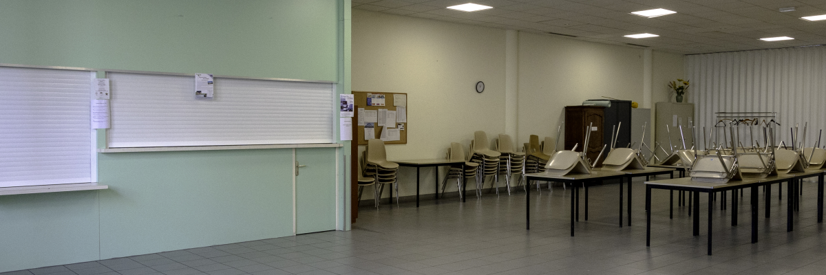 Salle avec tableaux, tables, chaises, piano, matériel de sport et affichage mural.