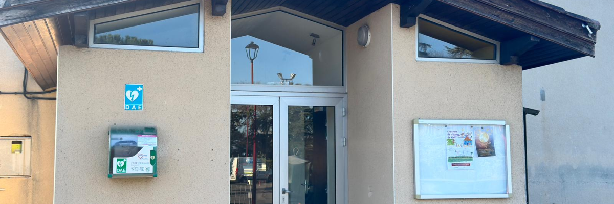 Bâtiment avec toit en pente, porte vitrée, fenêtre, boîte aux lettres, panneau d'information et éclairage extérieur.