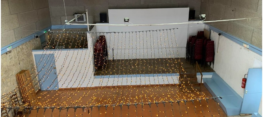 Pièce avec sol couvert de guirlandes lumineuses, filet, bancs et extincteur.