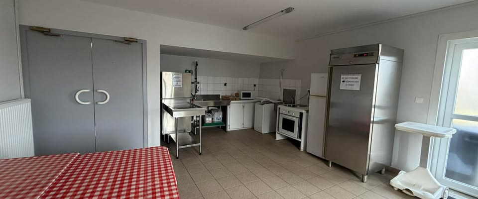 Cuisine avec table, évier, réfrigérateur, four, micro-ondes et chariot de service.