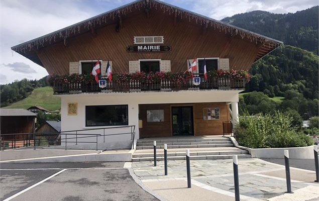 Mairie avec enseigne, drapeaux, fleurs et escalier.