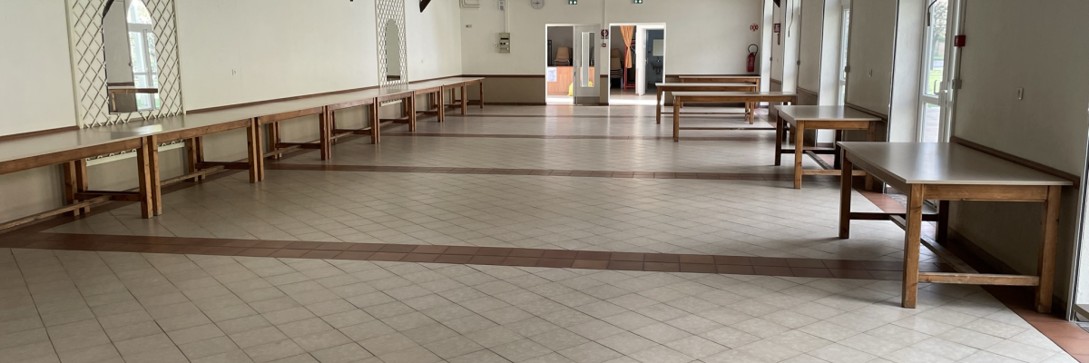 Salle avec tables, bancs, poubelles et portes.